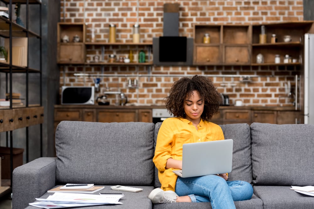 AttractiveYoungWomanWorkingWorkingWithLaptopOnCouch