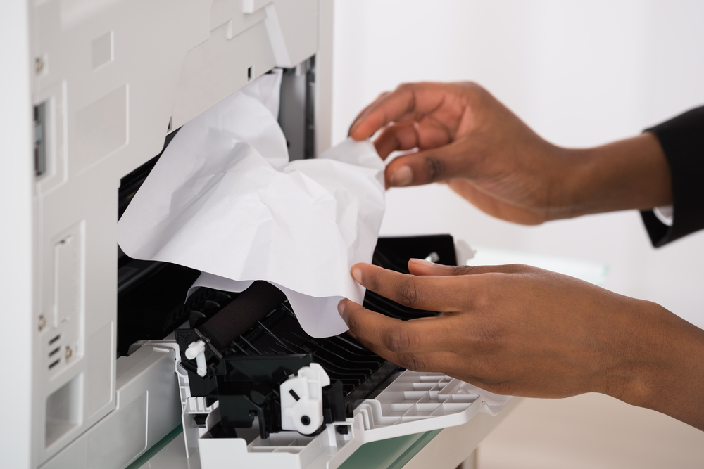 Close-upOfBusinesswomanHandRemovingPaperStuckedInPrinterAt