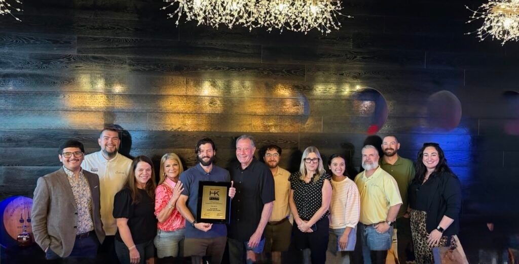 Img 4826 | platinum copier solutions Group of About 12 People Posing Together One Holding a Framed Award Plaque in a Dark Wood Wall Venue