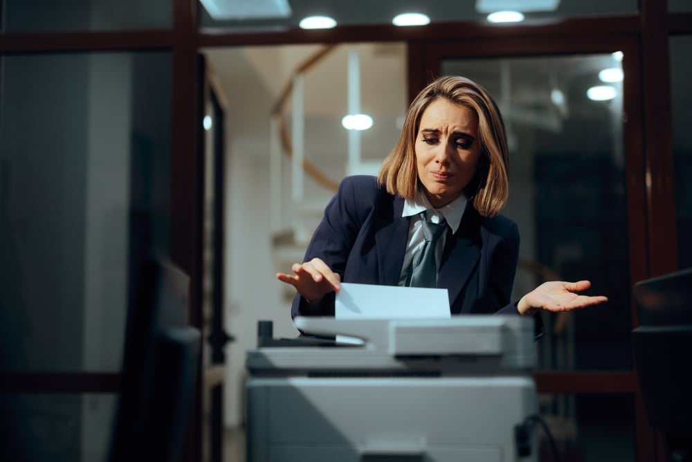 Frustrated Businesswoman Looking Confused while Trying to use a Printer Stressed female professional appearing perplexed while troubleshooting a malfunctioning copier